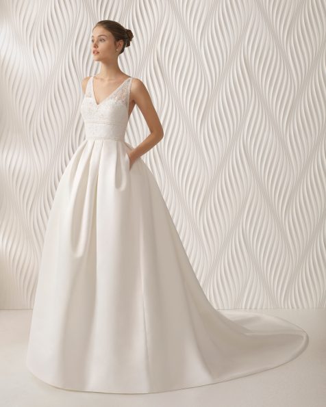 Vestido de noiva estilo clássico de tecido otomano, renda e brilhantes, com decote em V e costas decotadas com adorno de brilhantes.