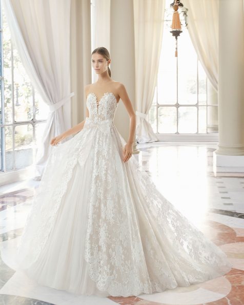 Robe de mariée style princesse en dentelle avec pierreries et tulle royal. Décolleté plongeant et décolleté dans le dos. Avec transparences et mancherons. Disponible en couleur naturelle/nude et naturelle. Collection ROSA CLARA COUTURE 2019.