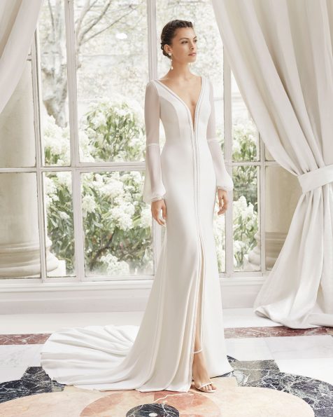Vestido de noiva corte reto de crepe. Decote deep-plunge, costas em V e manga comprida de crepe georgete. Com abertura frontal, adorno com trabalhado de ponto bordado e passamanaria. Disponível em cor natural. Coleção ROSA CLARA COUTURE 2019.