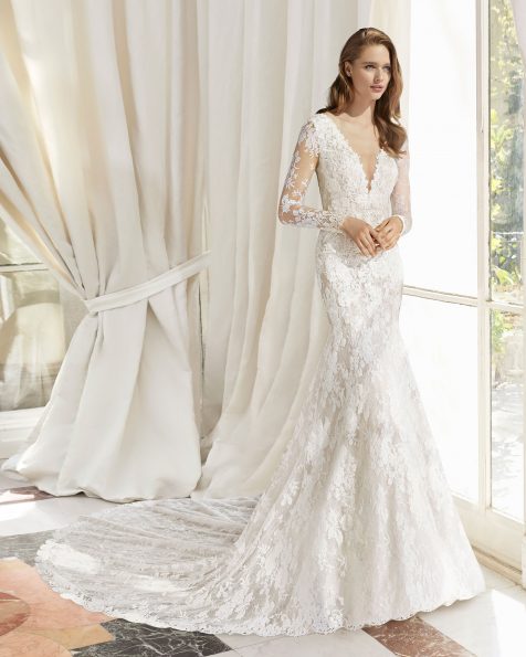 Abito da sposa dal taglio sirena di pizzo con applicazioni in guipure. Scollo profondo e schiena a V. Con trasparenze. Disponibile in colore naturale. Collezione ROSA CLARA COUTURE 2019.
