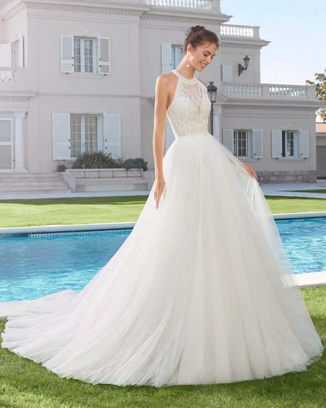 Vestido y sobrefalda de novia estilo línea A de tul y encaje pedrería. Escote halter y espalda con abertura redonda. Colección ROSA CLARA 2020.