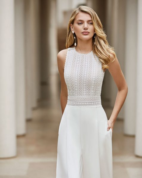 Leichtes Braut-Hosenkleid aus strassbesetzter Spitze und Crêpe. Hoher Rundhalsausschnitt und am Rücken gekreuzte Träger. Mit Eingrifftaschen, Knöpfen an den Schultern und Guipure-Verzierung am Gürtel. Kollektion ROSA CLARA COUTURE 2020.