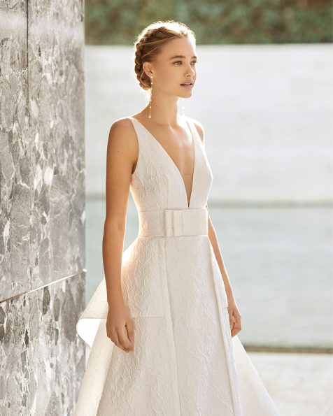 Vestido de noiva clássico de alta costura de corte reto em brocado íris com seda. Decote profundo, costas decotadas e alças. Com sobressaia e peplo em brocado íris com seda e adorno de laço na cintura. Coleção ROSA CLARA COUTURE 2021.