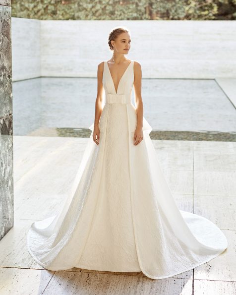 Vestido de noiva clássico de alta costura de corte reto em brocado íris com seda. Decote profundo, costas decotadas e alças. Com sobressaia e peplo em brocado íris com seda e adorno de laço na cintura. Coleção ROSA CLARA COUTURE 2021.