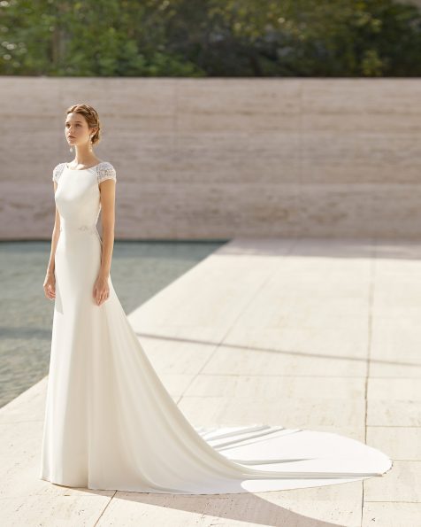 Vestit de núvia lleuger de crepè i pedreria. Suau escot barca, esquena escotada i màniga curta. Amb brodat joia a l’esquena, les mànigues i la cintura. Col·lecció ROSA CLARA COUTURE 2021.